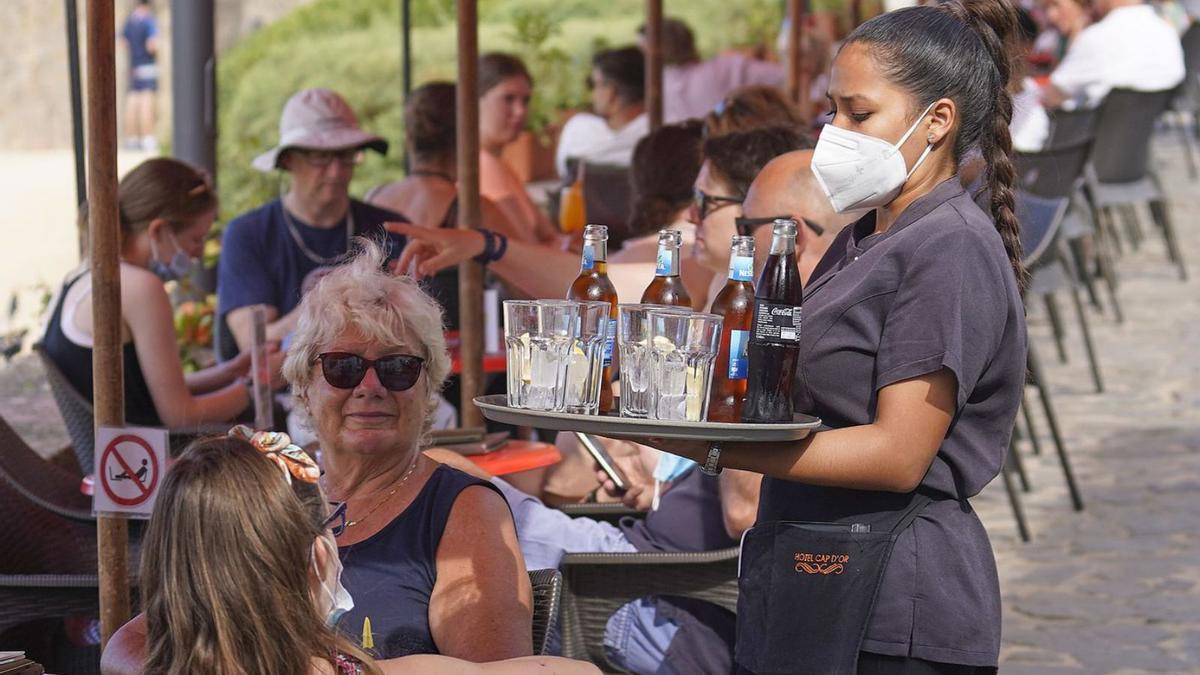 Una cambrera serveix beguda a uns turistes en un bar de Girona. | MARC MARTÍ