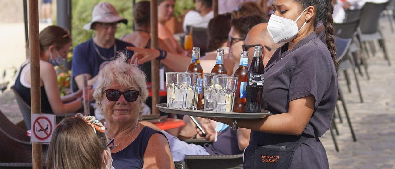 Una cambrera serveix beguda a uns turistes en un bar de Girona. | MARC MARTÍ