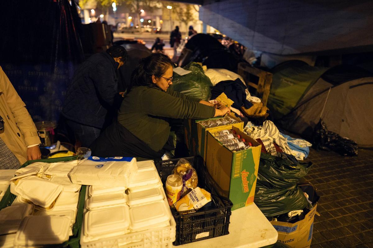 Voluntarios de distintas entidades privadas reparten comida para la cena de Nochebuena bajo la autopista C-31, donde aún duermen decenas de personas desalojadas del antiguo instituto B9