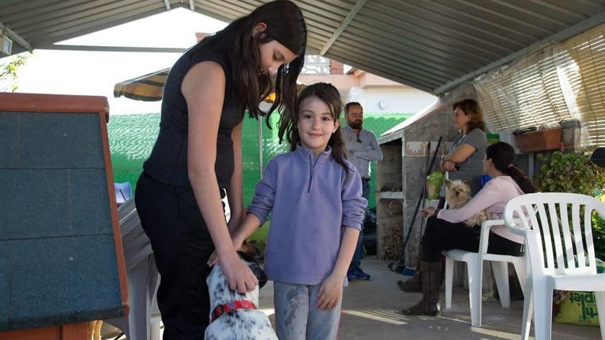 Desiré y Cristina juegan con uno de los perros de su familia.