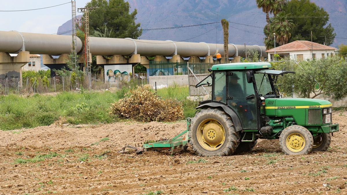 Un agricultor arando su campo frente a las tuberías del trasvase.