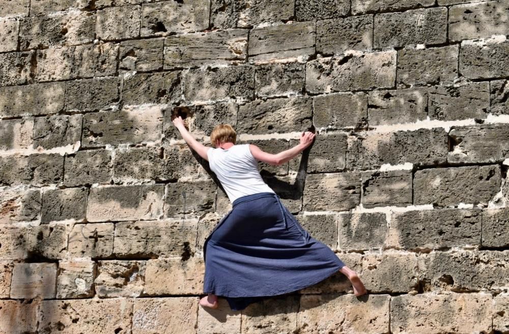 Una turista practica la escalada en las murallas de Palma descalza y con falda