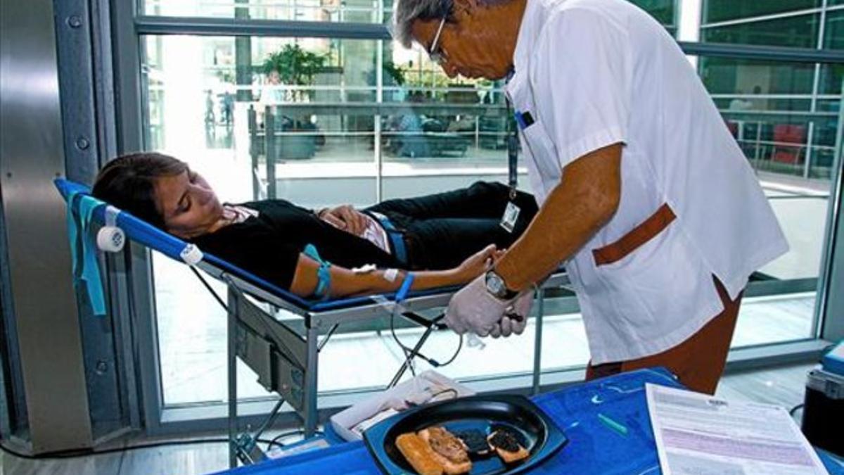 El enfermero Gabriel pincha a la joven Clara mientras las tapitas la esperan, ayer en el hospital de Sant Pau.