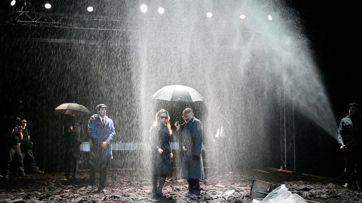 Dos actors de l'obra de teatre Hamlet, aguanten un paraigua mentre plou al mig de la imatge