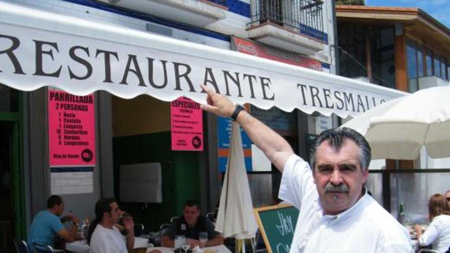 Chema Álvarez, mostrando el toldo de su negocio en pleno puerto candasín, ensuciado frecuentemente por las gaviotas.