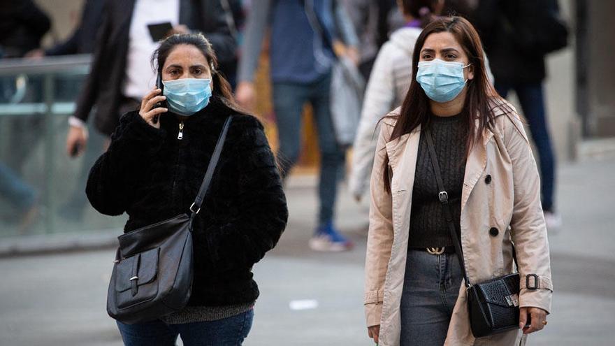 Dos mujeres pasean con mascarillas por Barcelona.