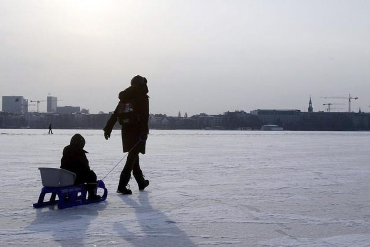 Una persona arrossega un trineu amb un nen sobre la superfície gelada del llac Außenalster (Alster exterior) a Hamburg, Alemanya. Una capa de 18 centímetres de gel permet practicar-hi el patinatge.
