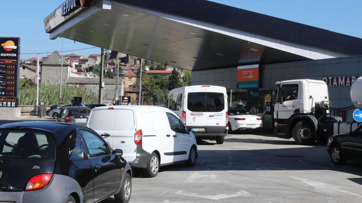 Coches con matrícula portuguesa haciendo cola, ayer, en una estación de servicio de Repsol en el concello de Tui (Pontevedra).