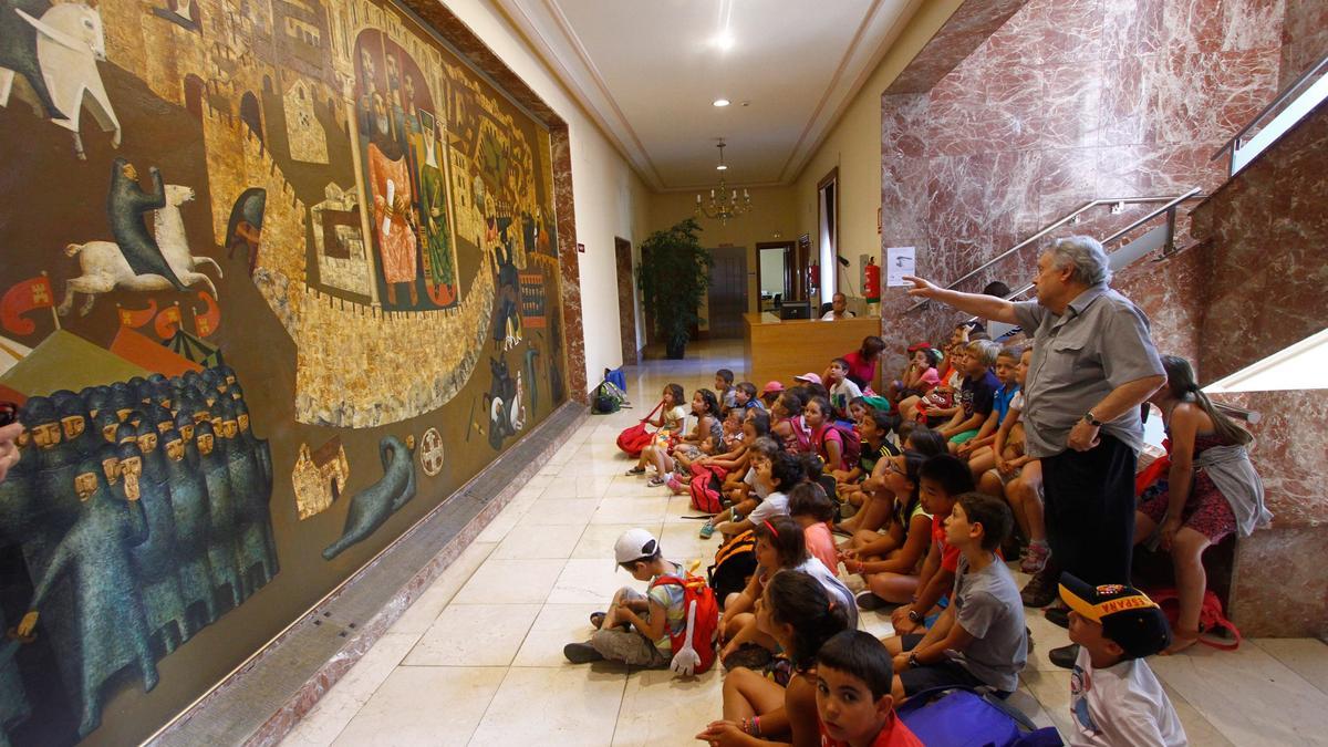 Antonio Pedrero explica a un grupo de niños su mural del cerco de cerco de la Subdelegación.