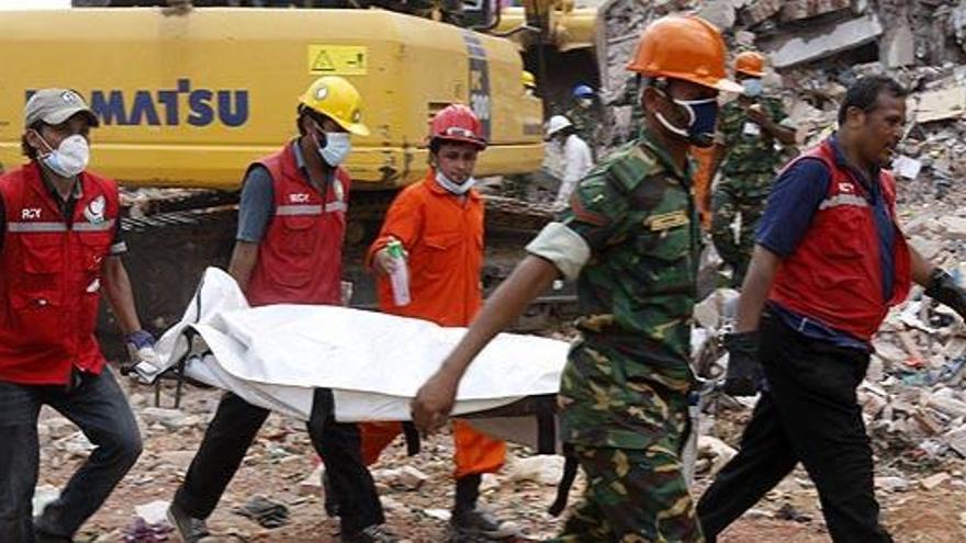 Miembros de los equipos de rescate, junto al edificio derruido.