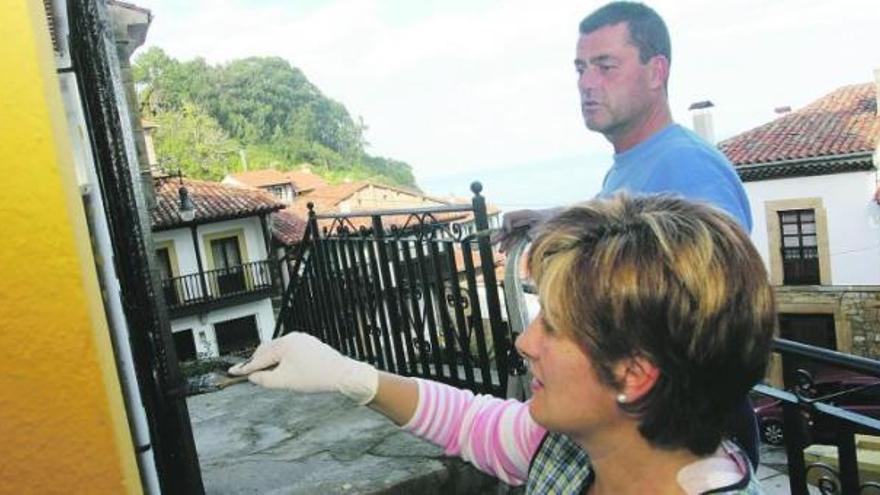 Alfonso Fernández y Esther Avín, pintando, ayer, los forjados de su casa situada en la calle Real de Lastres, que recorrerán los Príncipes.