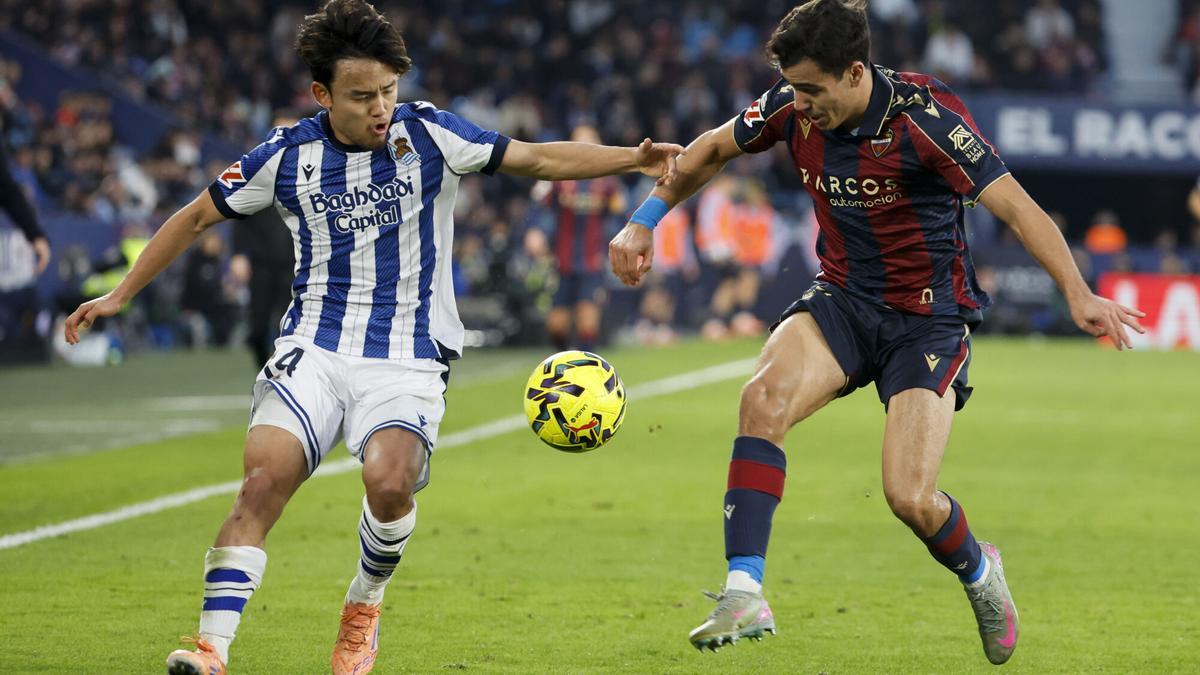 El centrocampista de la Real Sociedad Take Kubo disputa un balón con el defensa del Levante Manu Sánchez (d) durante el partido de LaLiga EA Sports entre Levante UD y Real Sociedad celebrado este sábado en el estadio Ciutat de València.