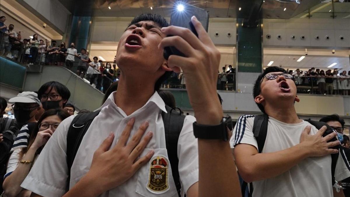 Unos jóvenes entonan el himno 'Gloria a Hong Kong' en un centro comercial.