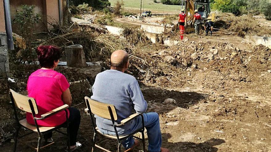 Catalina Servera y su pareja observan cómo trabajan los operarios y bomberos en Sant Llorenç.