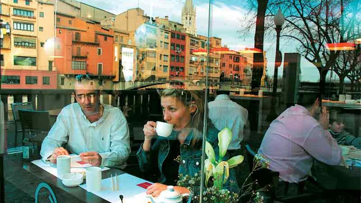 Siluetas de las casas del Oymar reflejadas en la vidriera del café de la Riba.