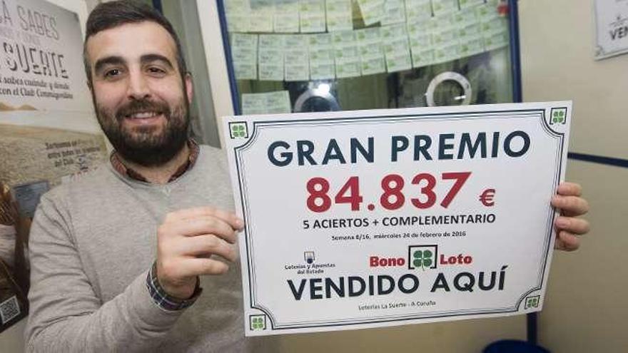 El lotero muestra el cartel con el premio entregado.