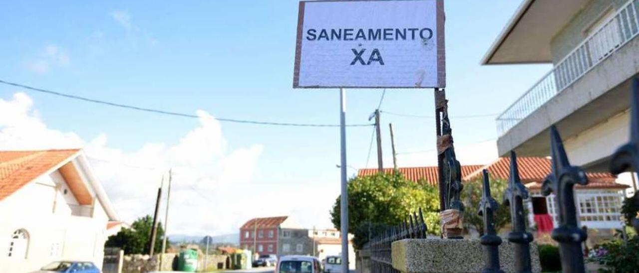 Uno de los carteles instalados por la parroquia de Mourente para demandar el saneamiento. // G. Santos