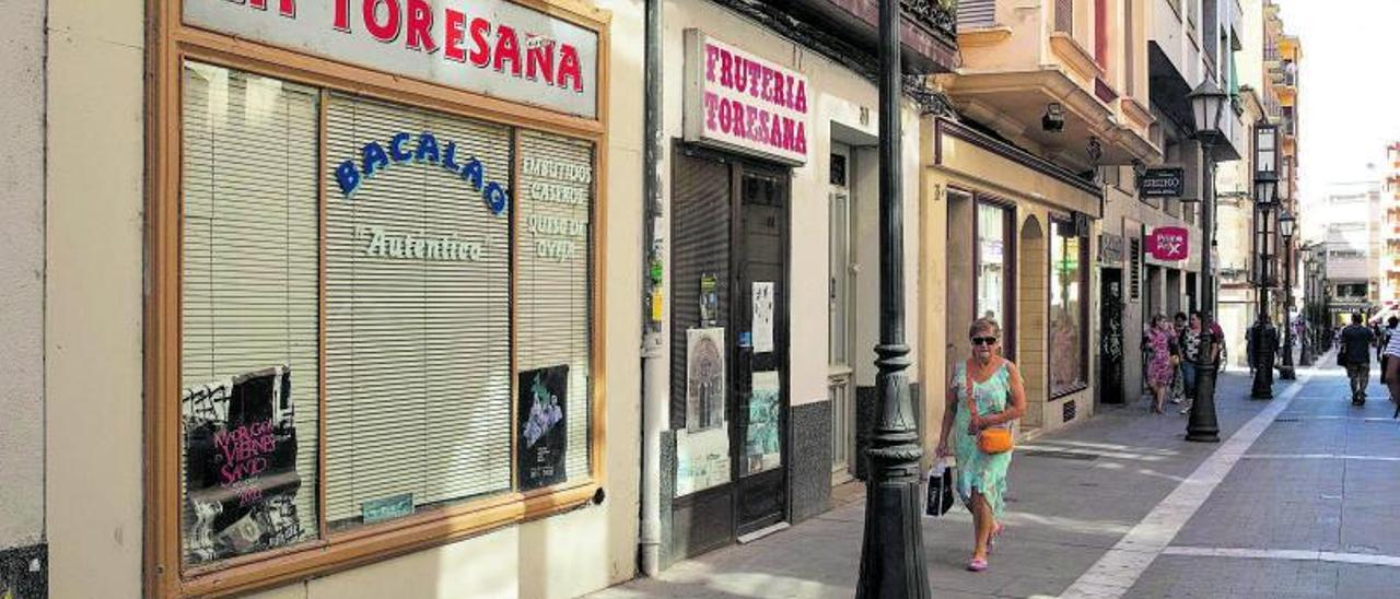 Una ciudadana pasea por uno de los 24 locales cerrados de la calle San Torcuato de Zamora. | Ana Burrieza