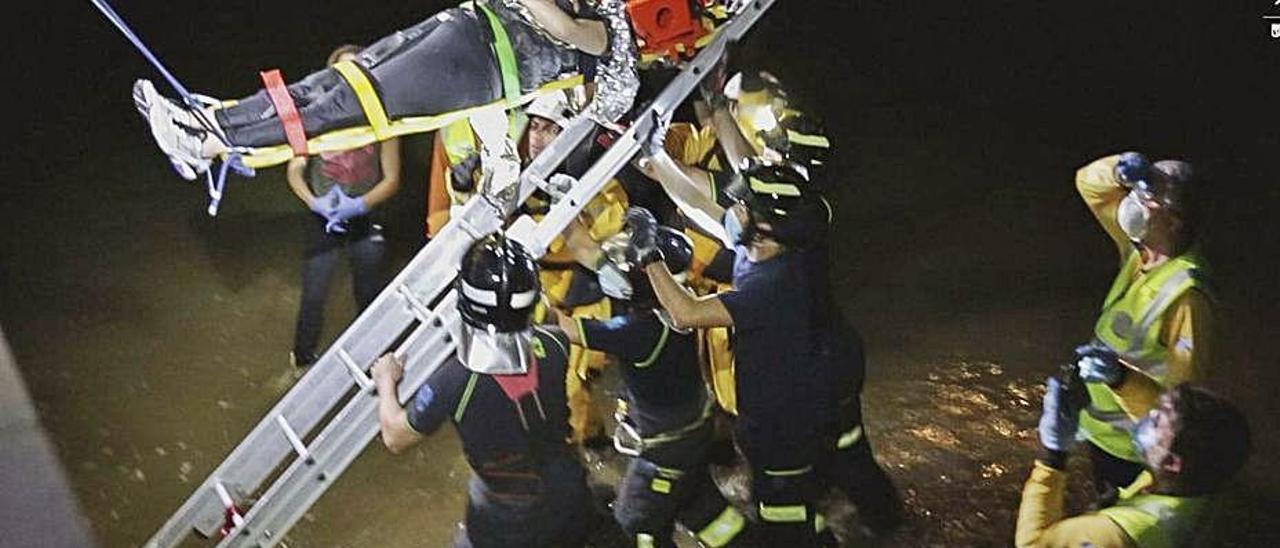 Los bomberos, durante el rescate de la mujer que se precipitó al río Manzanares.