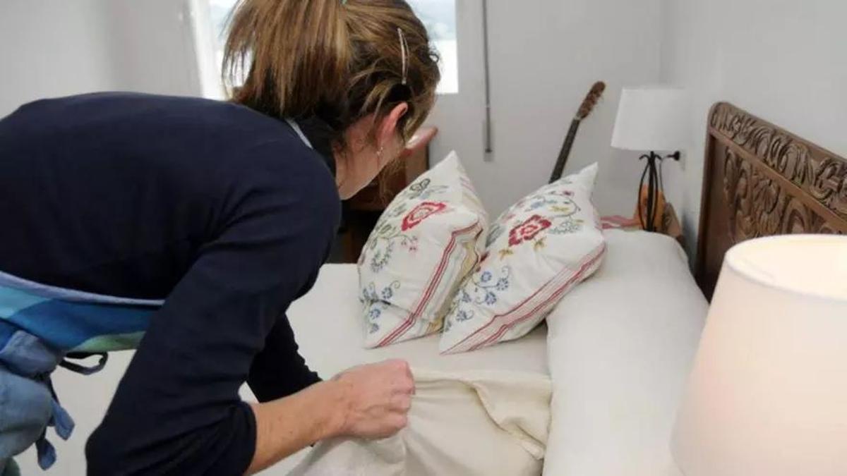 Una mujer ama de casa haciendo la cama.