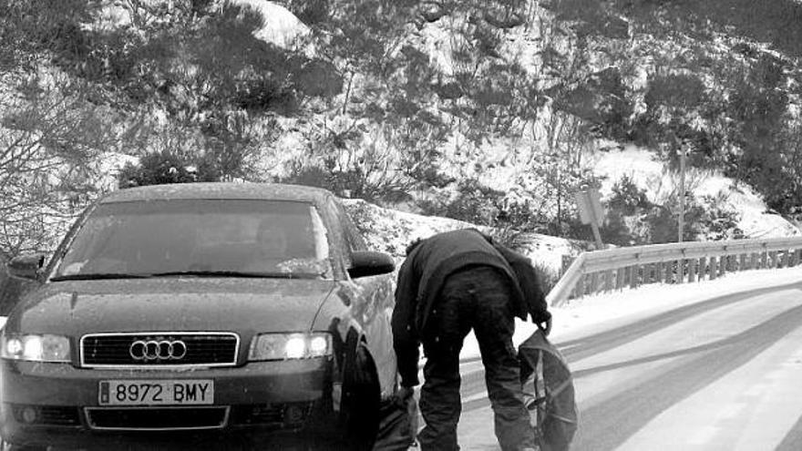 Un hombre coloca las cadenas en su coche para continuar trayecto hacia el puerto de San Isidro, ayer, en plena nevada.