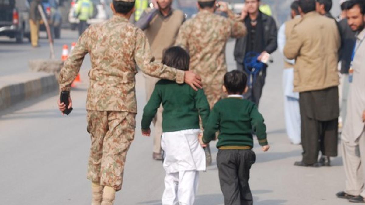 A soldier escorts schoolchildren after they were rescued from the Army Public School that is under attack by Taliban gunmen in Peshawar
