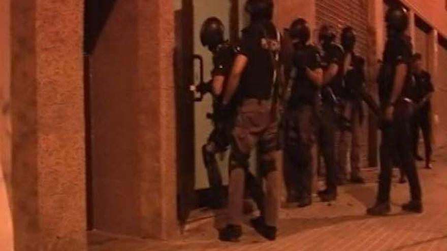 Agentes de la Policía Nacional, durante el asalto a una de las viviendas de los sospechosos de robar pisos en A Coruña, y la detención de uno de ellos.