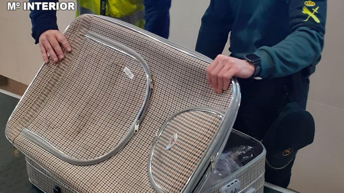 Un agente revisa la maleta en la que encontraron los 100.000 euros.