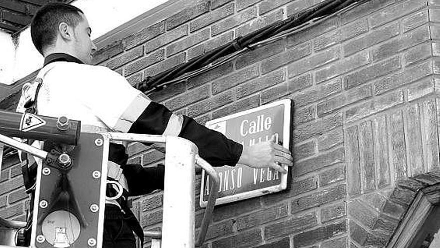 Un empleado municipal retirando la placa de la calle Camilo Alonso Vega, al mediodía de ayer.