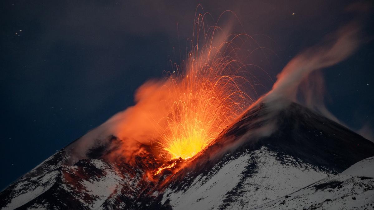 Columnas de humo y lava se elevan desde el volcán Etna, cubierto de nieve