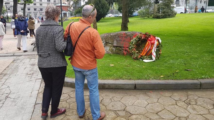 Dos paseantes observando los daños provocados en el monumento.