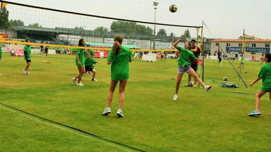 Varios niños juegan al voleibol en el campo de O Vao.