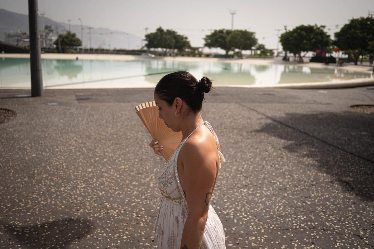 Una ciudadana se abanica debido al calor mientras pasea junto al lago de la plaza de España.
