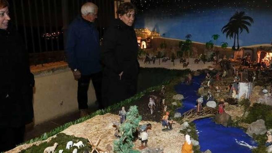 Varios visitantes observan el belén de la iglesia de San Martín de Laspra.