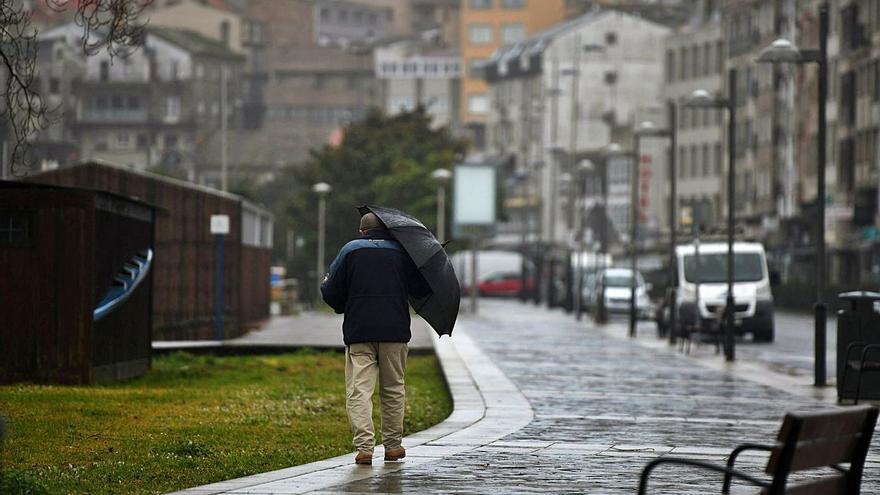 Un hombre con un paraguas se protege de la lluvia el mes pasado en Baltar (Portonovo). | // GUSTAVO SANTOS
