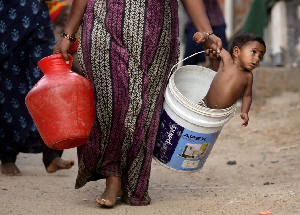 A woman carries her son in a bucket after ...
