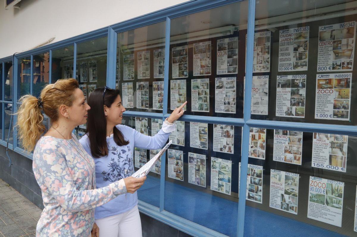Dos mujeres observan carteles de una inmobiliaria de Córdoba.