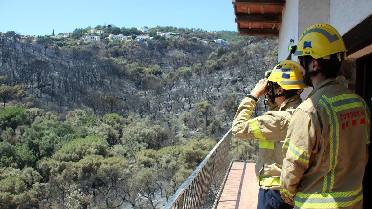 Els bombers del GREC utilitzant uns prismàtics des d'una casa de Mas Ambrós, Calonge