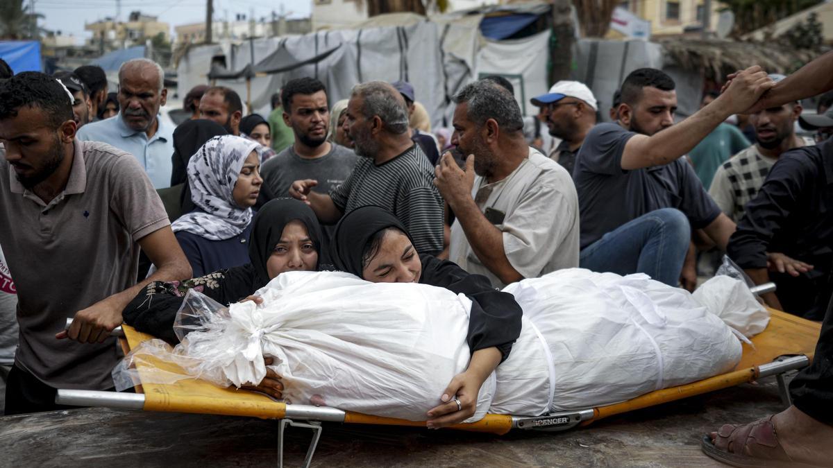 Dos mujeres palestinas abrazan el cadáver de un familiar fallecido en un bombardeo israelí, este jueves en el hospital de Deir el Balah, en Gaza.