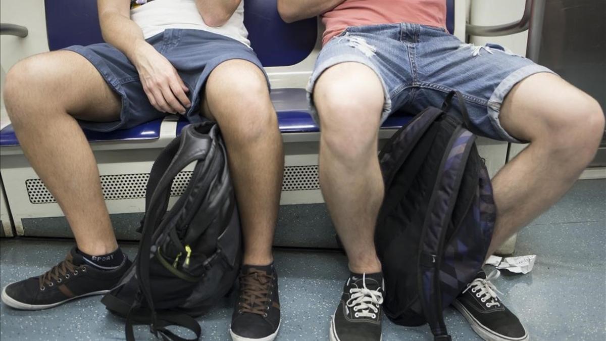 Dos pasajeros del metro de Barcelona ocupando su asiento y parte del contiguo.