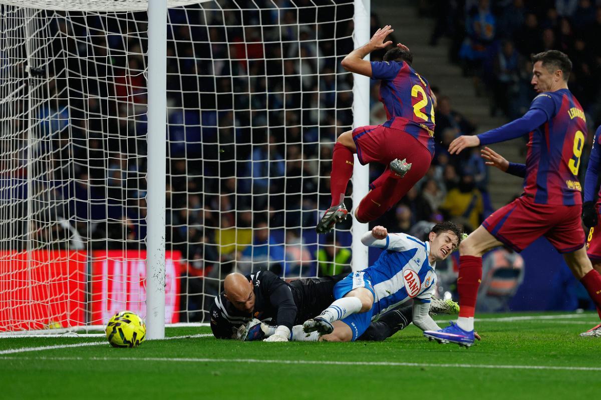 Eric García, del Barcelona, ​​arriba al centro, salta sobre el portero del Espanyol, Marko Dmitrovic, izquierda, y Pol Lozano durante el partido de fútbol de la Liga española entre el RCD Espanyol y Barcelona en Barcelona, ​​España, el sábado 3 de enero de 2026. (Foto AP/Joan Monfort)