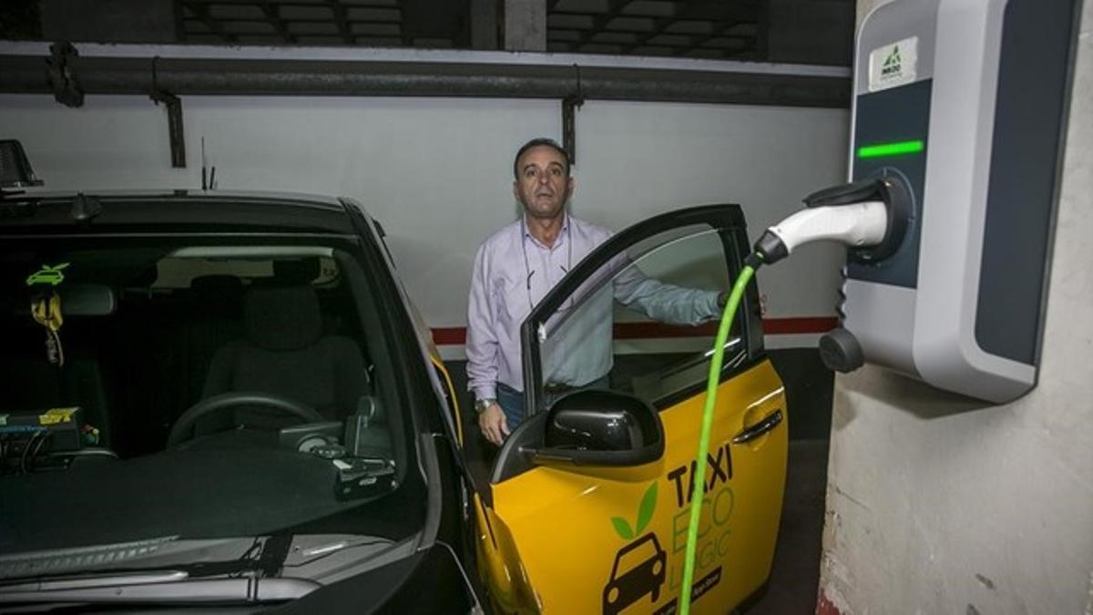 El taxista Paco Guerrero, junto al punto de recarga instalado en su plaza de aparcamiento en Barcelona.