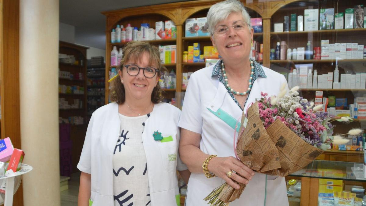 La farmacèutica Lourdes Taberner i l’auxiliar Anna Suñer amb el ram de flors i el pin de l’AV Enric Morera.