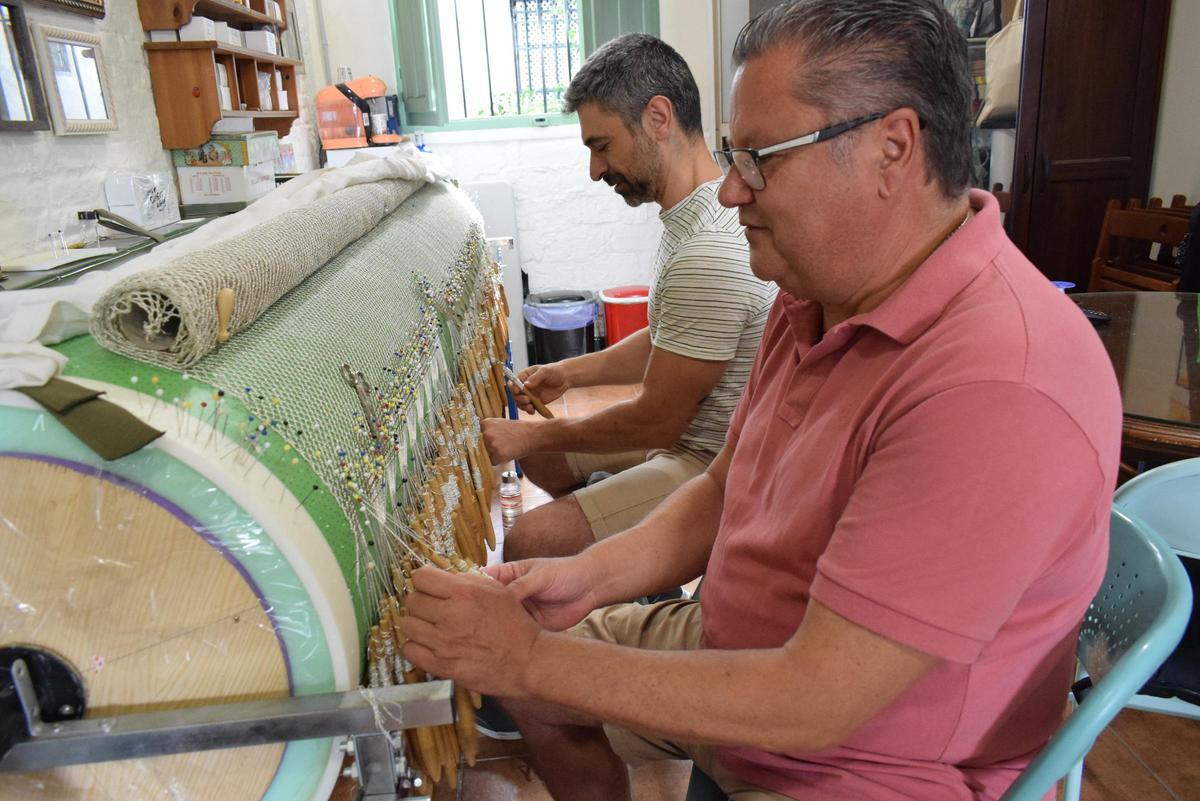 Alfonso Aguilar (i) trabajando en su taller de encaje de bolillos