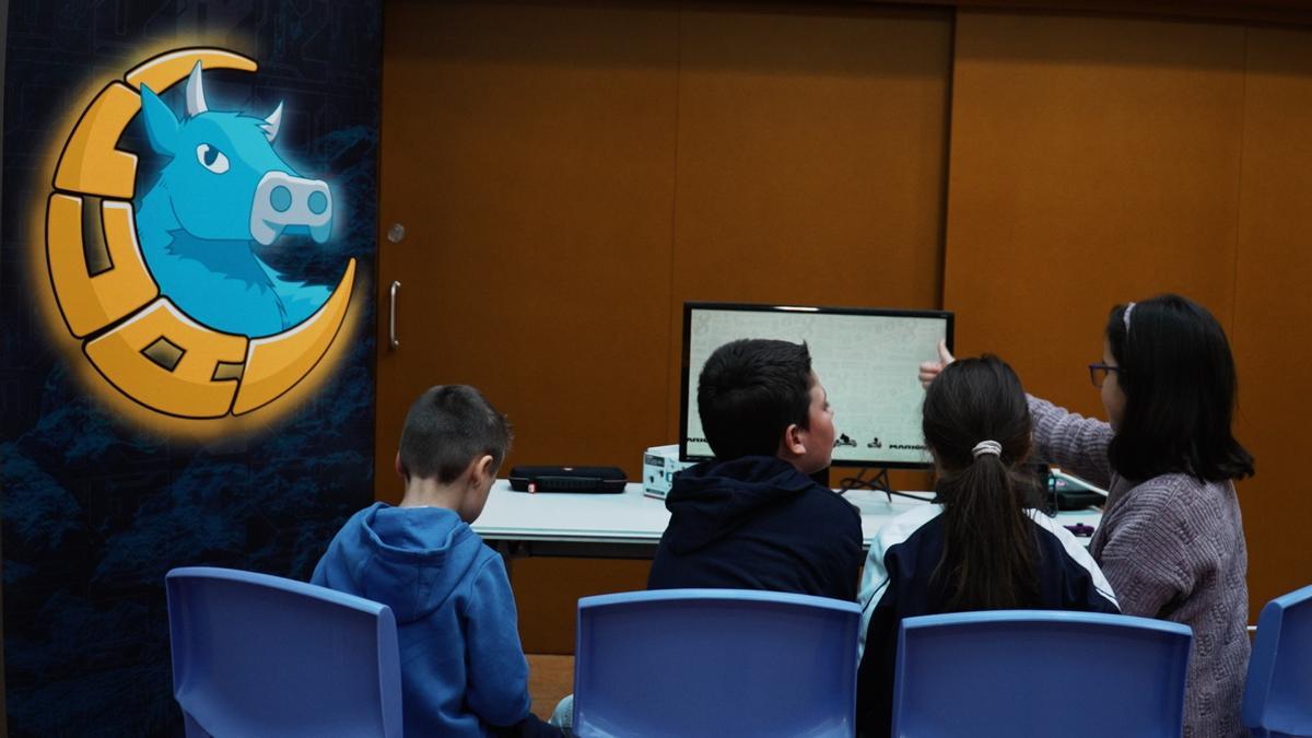 Menores participan en un taller de Lua Gaming. A la izq., el logo de la empresa.