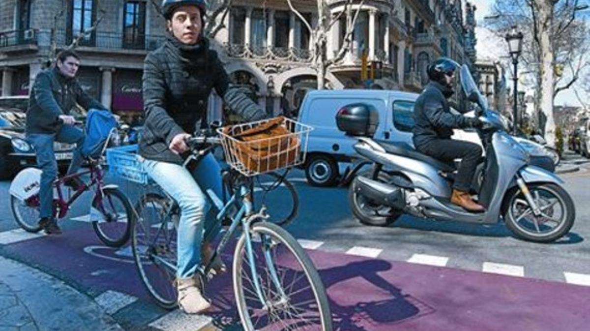 Una ciclista con casco y otro sin, ayer en Consell de Cent con paseo de Gràcia.