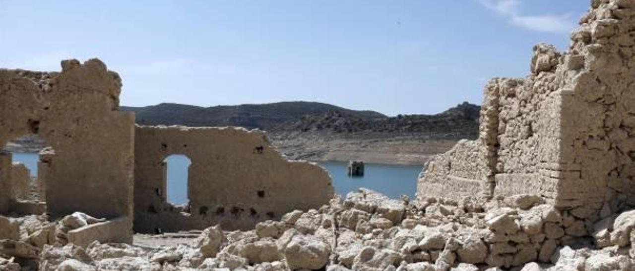 Parte del patrimonio destrozado por las aguas del pantano y, al fondo, el campanario de la antigua iglesia de Tous.