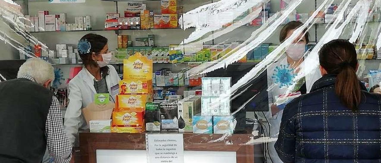 Mascarillas y mamparas de plástico como protección en la farmacia de Priegue, en Nigrán. // FdV