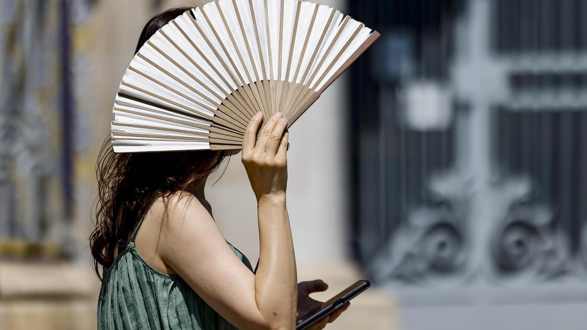 Una mujer se proteje del sol con un abanico.
