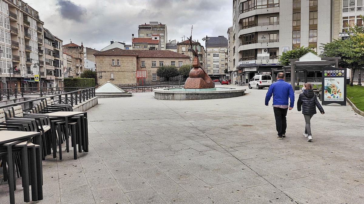 Dos personas pasean por una plaza de O Carballiño completamente vacía.   | // CARLOS PETEIRO